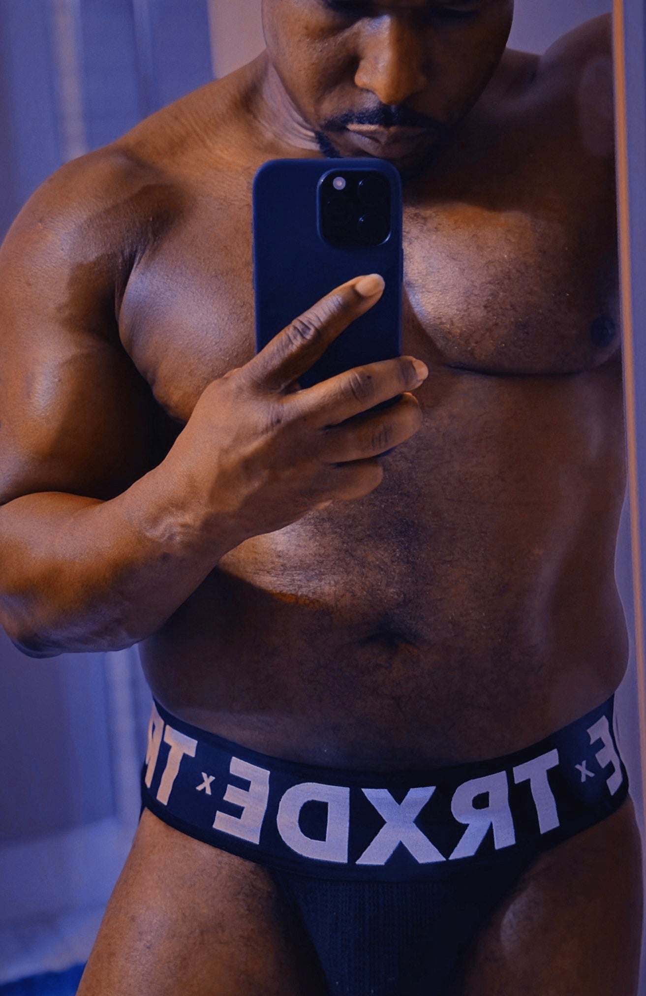Muscular man taking a mirror selfie wearing TRXDE underwear.