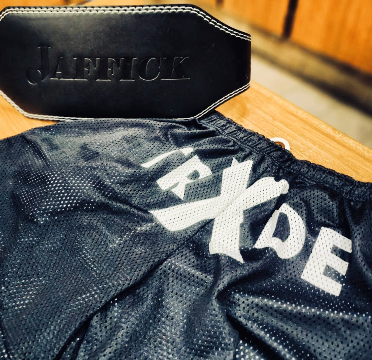 Black waist belt with 'Jafelick' branding on a black mesh garment with 'RXXDE' text.