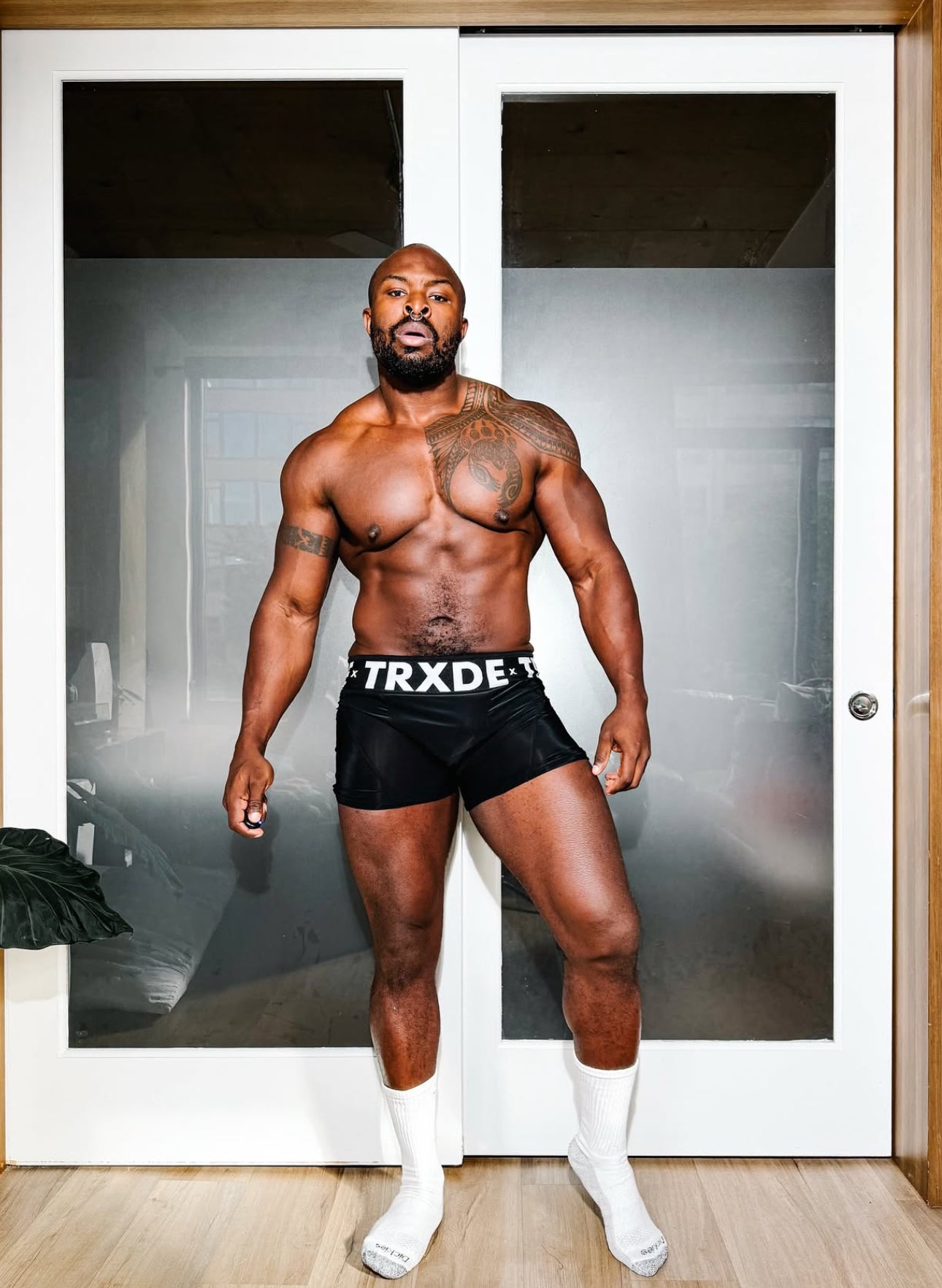 Man wearing black shorts with 'TRXDE' branding in a room with white doors.