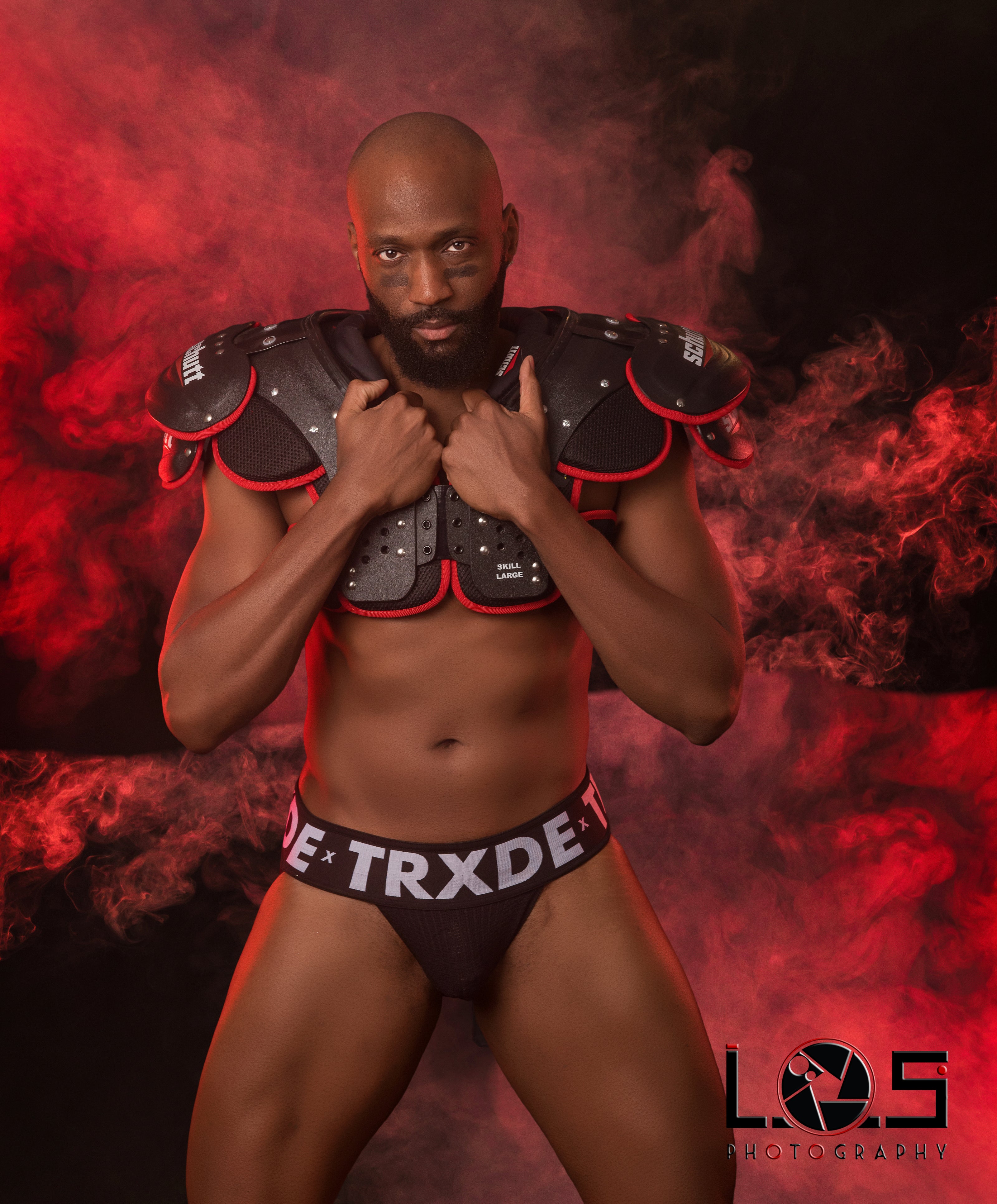 Man wearing black athletic wear with red accents against a dark background