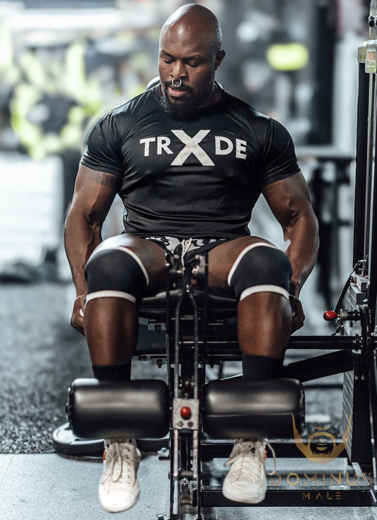 Man exercising on a leg press machine wearing a black 'TRXDE' shirt.