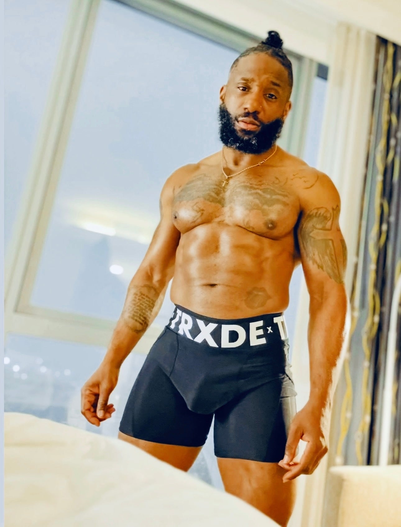 Man wearing black boxer briefs with visible branding in a room.