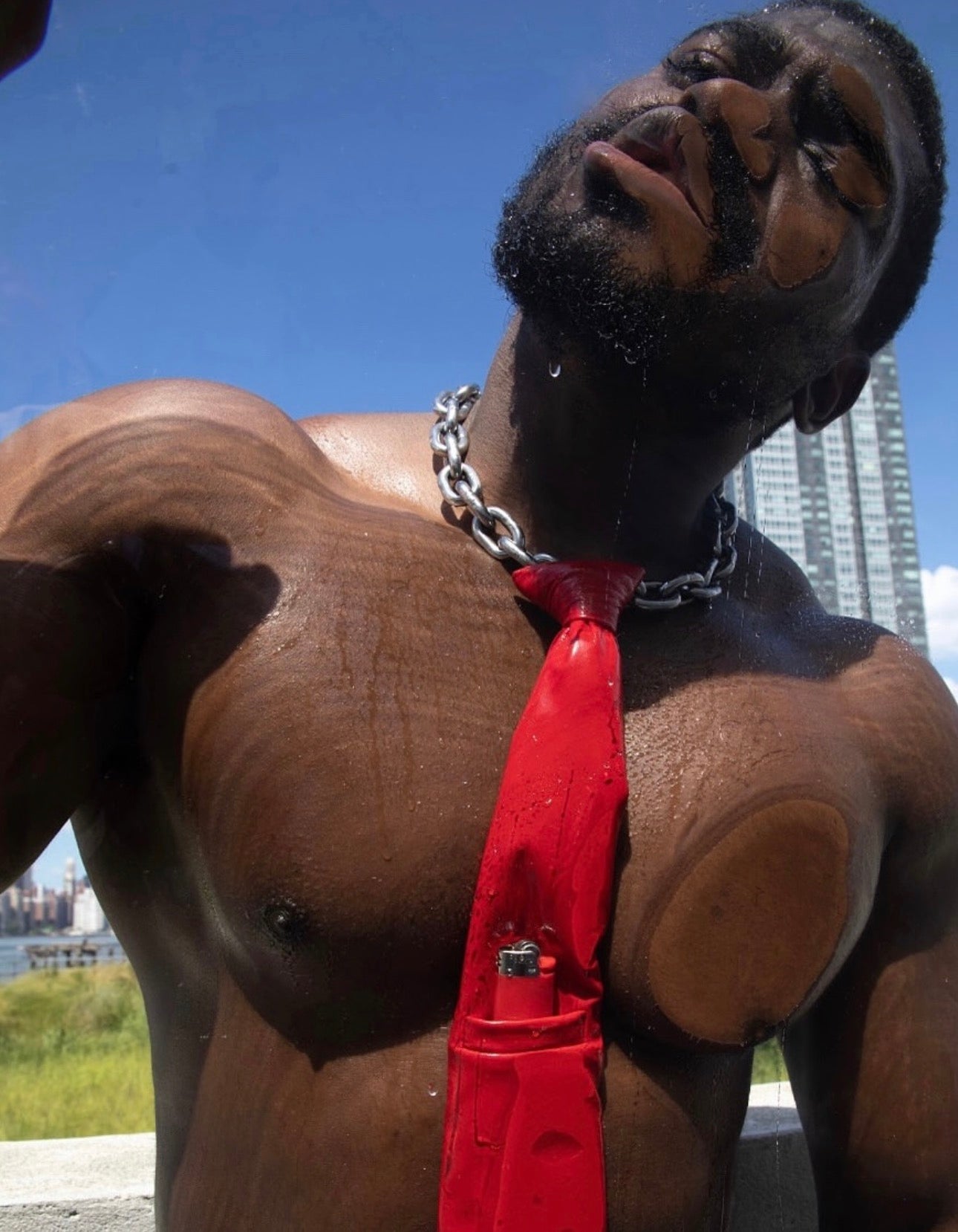 Person with a red leash and chain around their neck against a cityscape background